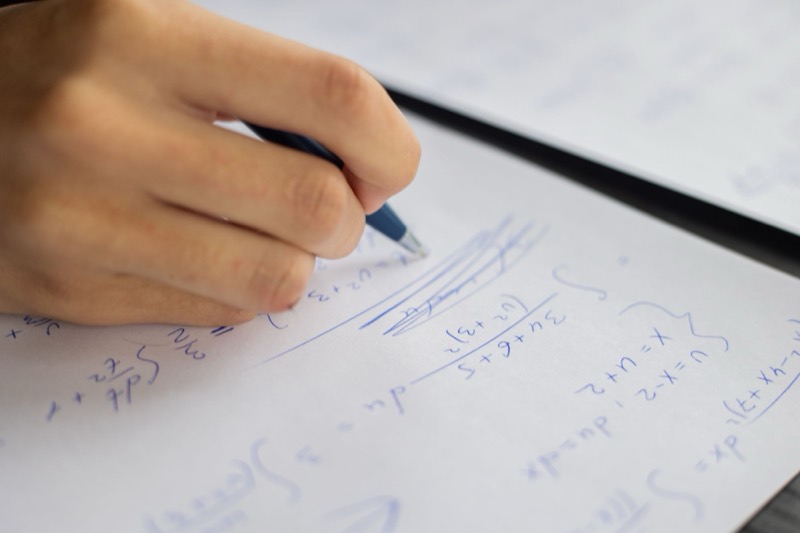 Hands writing maths working in a notebook